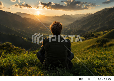 a man sits on the grass and looks at nature, a view of the hills and valley at sunset, a beautiful landscape, the concept of rest and relaxation a man sits on the grass and looks at nature, a view of the hills and valley at sunset, a beautiful landscape, the concept of rest and relaxation 118873559