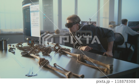 Archaeologist in VR headset studies ancient skeleton using augmented reality 118878308