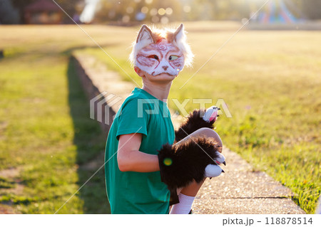 Confident young little kid boy wear cat furry mask enjoy have fun playing outdoors in forest street park. Children therian wild animal character trendy fan culture. Teenager social expression hobby 118878514