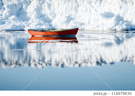 A solitary orange boat floating calmly on a still lake surrounded by majestic snow covered mountains during a clear winter day 118879630