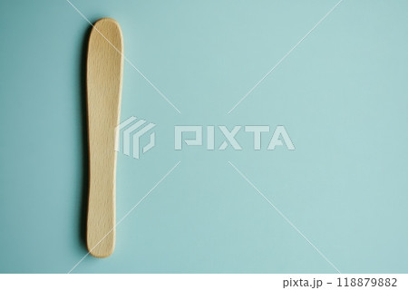 Simple wooden spatula placed against a light blue background for kitchen or cooking purposes Simple wooden spatula placed against a light blue background for kitchen or cooking purposes 118879882