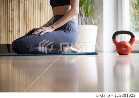 Fit woman sitting on an exercise mat taking a break from a workout 118881022