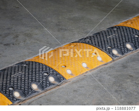 yellow and black traffic safety speed bump on a concrete road at parking lot. High quality photo yellow and black traffic safety speed bump on a concrete road at parking lot. High quality photo 118881077