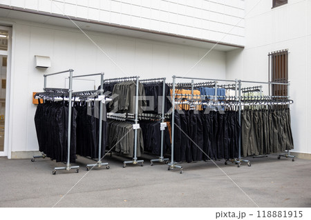 外に置かれたスチールパイプハンガーラックに掛けられたたくさんの新しい服 118881915
