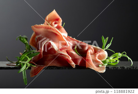 Prosciutto with rosemary on a black background. Prosciutto with rosemary on a black background. 118881922