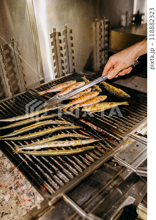 Chef grilling fresh fish on barbecue grill, perfect for seafood and culinary scenes 118882323