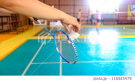 White badminton shuttlecocks being served by hands in indoor badminton court. Concept for enhancing badminton competition exercise and its lovers. White badminton shuttlecocks being served by hands in indoor badminton court. Concept for enhancing badminton competition exercise and its lovers. 118883479
