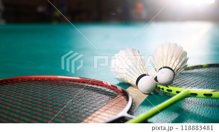 White badminton shuttlecocks and badminton rackets on green floor indoor badminton court. Concept for badminton competition and its lovers. White badminton shuttlecocks and badminton rackets on green floor indoor badminton court. Concept for badminton competition and its lovers. 118883481