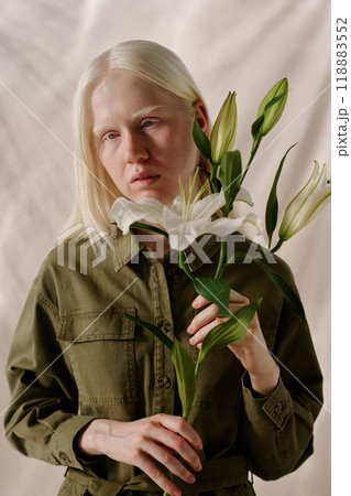 Vertical portrait of modern young woman with long white hair holding fresh lily flowers Vertical portrait of modern young woman with long white hair holding fresh lily flowers 118883552