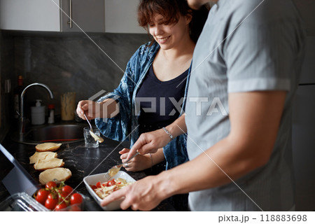 A young couple cooks food together at home using a tablet. A young couple cooks food together at home using a tablet. 118883698