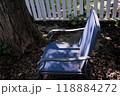 Blue chair in sunlight by tree and fence 118884272
