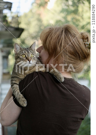 woman and cat. happy European woman lovingly hugs her cute tabby cat at home, 118884290