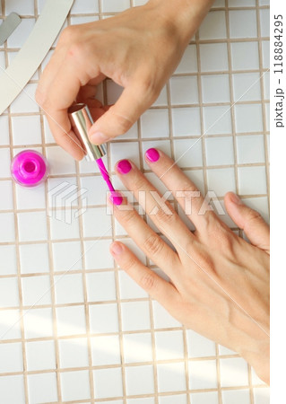 woman paints nails at home, manicures takes care of hands. bright pink nail polish 118884295