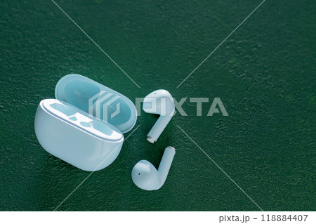 Wireless headphones on green background. Wireless, headphone in charging box. 118884407