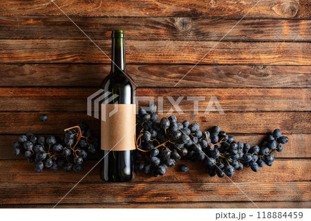 Blue grapes and bottle of red wine on an old wooden table. 118884459