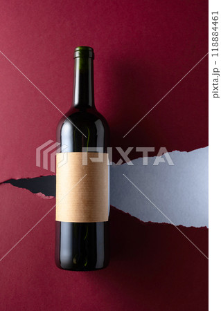 Bottle of red wine with old empty label on a dark red background. 118884461