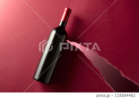 Bottle of red wine on a dark red background. 118884462