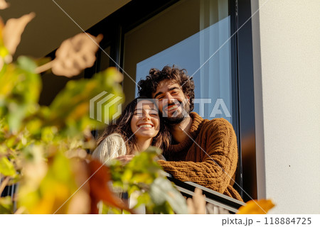 A man and woman are smiling at the camera from a balcony 118884725