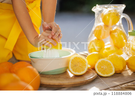A pitcher of lemonade with sliced lemons and oranges on a table 118884806