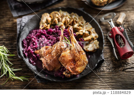 Portion of roast duck leg red cabbage homemade dumplings on plate and red wine on the background Portion of roast duck leg red cabbage homemade dumplings on plate and red wine on the background 118884829