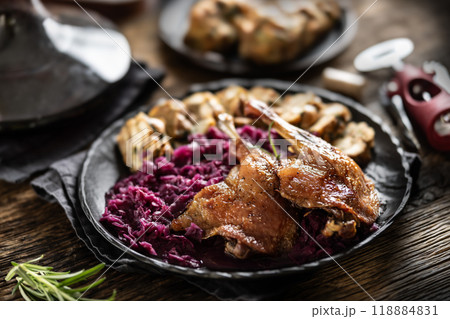 Portion of roast duck leg red cabbage homemade dumplings on plate and red wine on the background 118884831