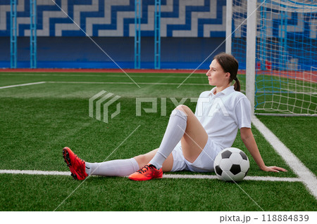 Football player sitting on the grass of a football field, break after a football match Football player sitting on the grass of a football field, break after a football match 118884839
