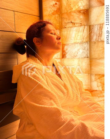 Portrait Millennial woman relaxing in a sauna room. Female enjoys a peaceful moment in spa hotel vacation. Self care, mindfulness and wellness concept Portrait Millennial woman relaxing in a sauna room. Female enjoys a peaceful moment in spa hotel vacation. Self care, mindfulness and wellness concept 118885691