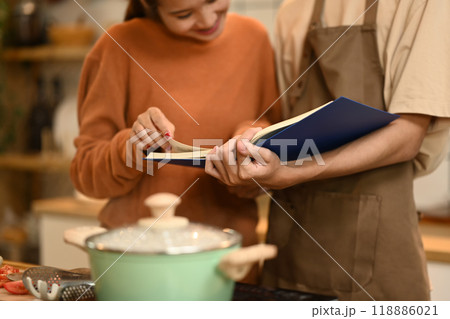 Young couple looking at a recipe book, enjoying the process of cooking together in the kitchen 118886021