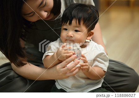 Little baby boy sitting on mother lap and drinking milk from bottle. Childhood and nurturing care concept 118886027