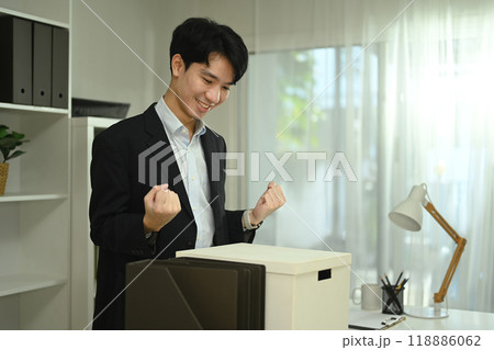Happy asian male office worker with box of his belongings moving into a new office 118886062