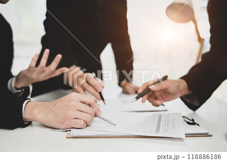 Cropped shot group of businesspeople analyzing data presented on a clipboard at meeting room 118886186