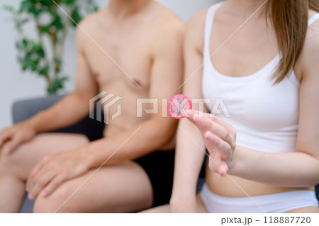 コンドームを持つ若い女性の手　避妊具を持つ男女カップル　夫婦　妊活　性的同意 118887720
