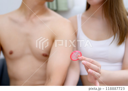 避妊具着用を勧める女性　コンドームを持つ若い女性の手　避妊具を持つ男女カップル　夫婦　妊活　性的同意 118887723