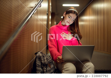 Cute young girl sitting on the steps and having a video call 118887792