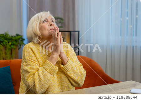 Worried senior elderly woman praying sincerely with folded arms asking God for help, begging apology Worried senior elderly woman praying sincerely with folded arms asking God for help, begging apology 118888344
