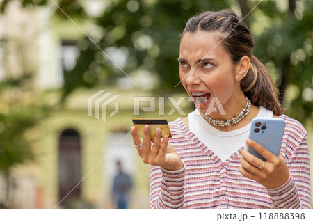 Shocked woman trying pay online shopping with smartphone blocked credit card lack of money balance Shocked woman trying pay online shopping with smartphone blocked credit card lack of money balance 118888398
