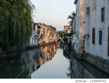 Tranquil evening by the canal in a picturesque village with traditional architecture reflecting on the water 118888702