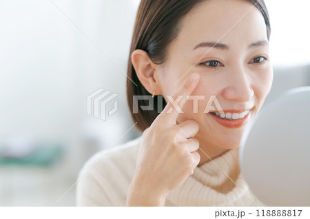 鏡で目元を見て微笑むミドルの女性 118888817