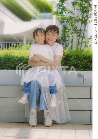 街中で寄り添って座る親子 118890444