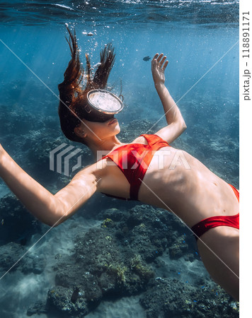 Woman with mask swims underwater in blue sea. 118891171