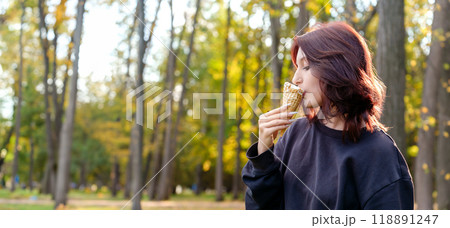 refreshing taste of ice cream brings a smile to the face of a female figure as she licks the frozen confection in a serene outdoor locale refreshing taste of ice cream brings a smile to the face of a female figure as she licks the frozen confection in a serene outdoor locale 118891247