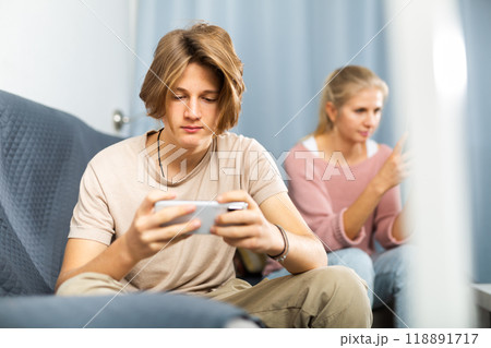 Excited teen boy playing online game on cell phone at home Excited teen boy playing online game on cell phone at home 118891717