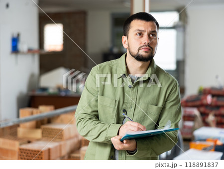 Engineer planning renovation works at building site, looking at papers Engineer planning renovation works at building site, looking at papers 118891837