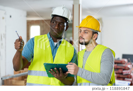 Two builders talking on indoor construction site 118891847
