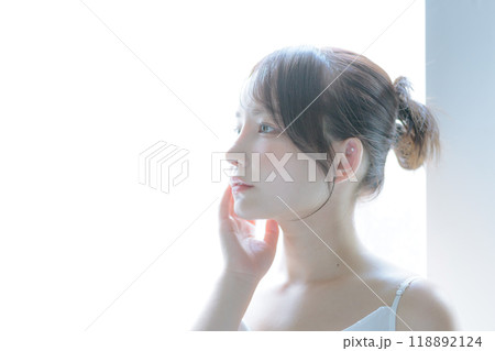 朝日を浴びてスキンケアをしている若い女性 朝日を浴びてスキンケアをしている若い女性 118892124