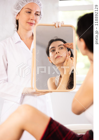 Young woman examining her face after cosmetic procedure 118892129
