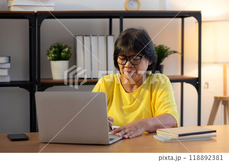 Senior asian woman working with writing on note and study while laptop on desk office. 118892381