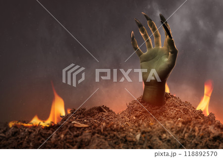Witch hand with long black nail coming out from grave ground with a fire in the background. The hand appearing to be a evil, satan, zombie or a monster hand Witch hand with long black nail coming out from grave ground with a fire in the background. The hand appearing to be a evil, satan, zombie or a monster hand 118892570