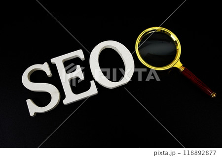 Seo words (Search Engine Optimization) letters with magnifying glass on black background 118892877