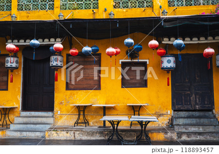 facade of an ancient Asian yellow cafe house decorated with Chinese hanging lanterns in old town in Hoi An in Vietnam in Asia 118893457